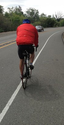 cyclist riding on a wide paved roadway shoulder