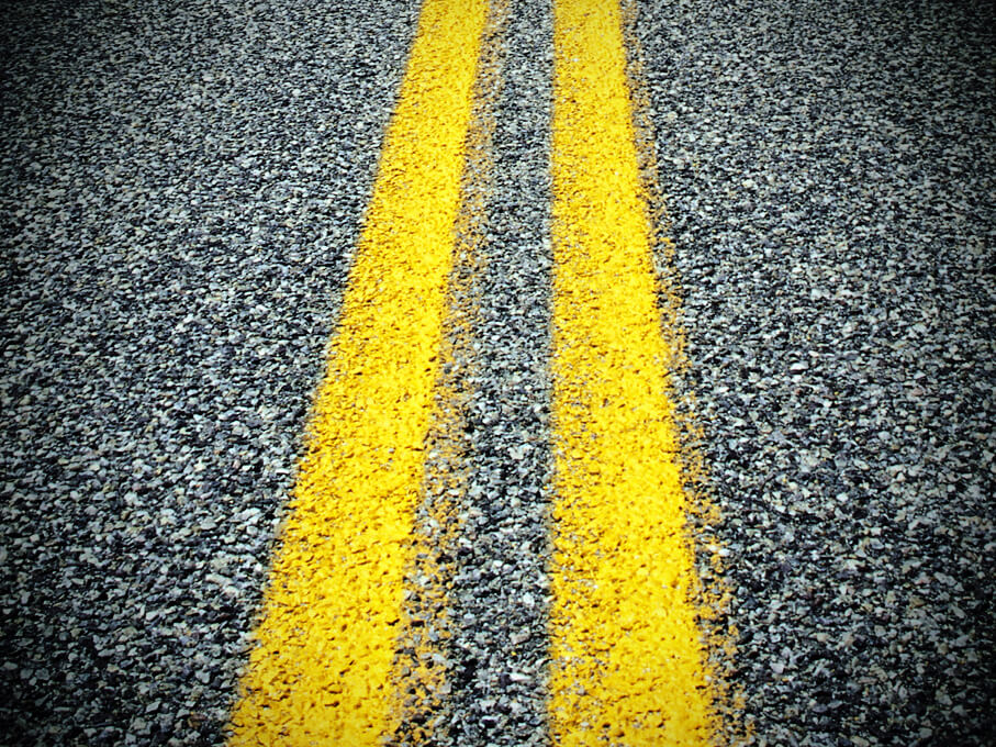 closeup of asphalt pavement and yellow lines