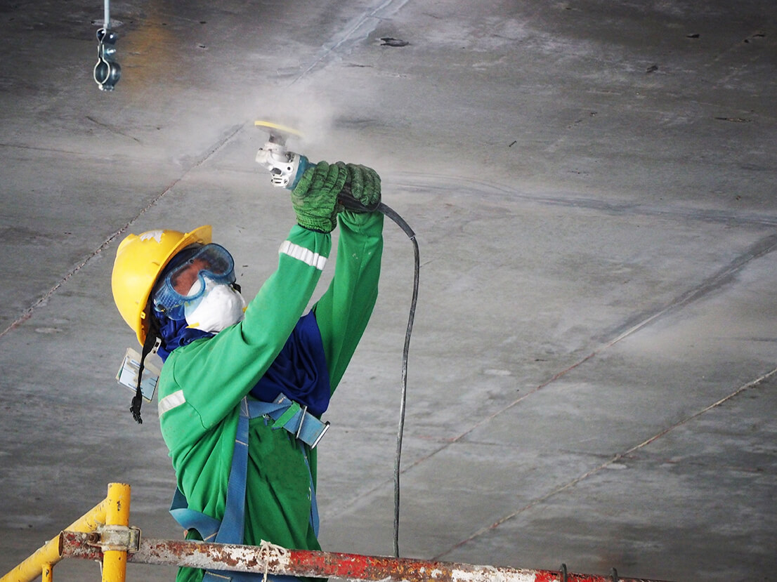 construction worker using a power grinder on concrete