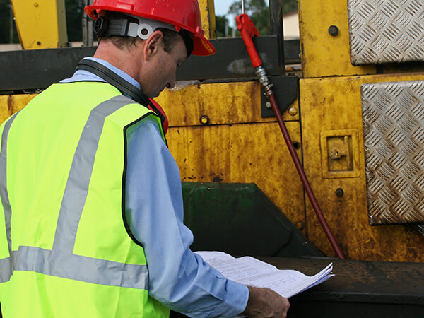 construction engineer looking a plans next to some heavy equipment