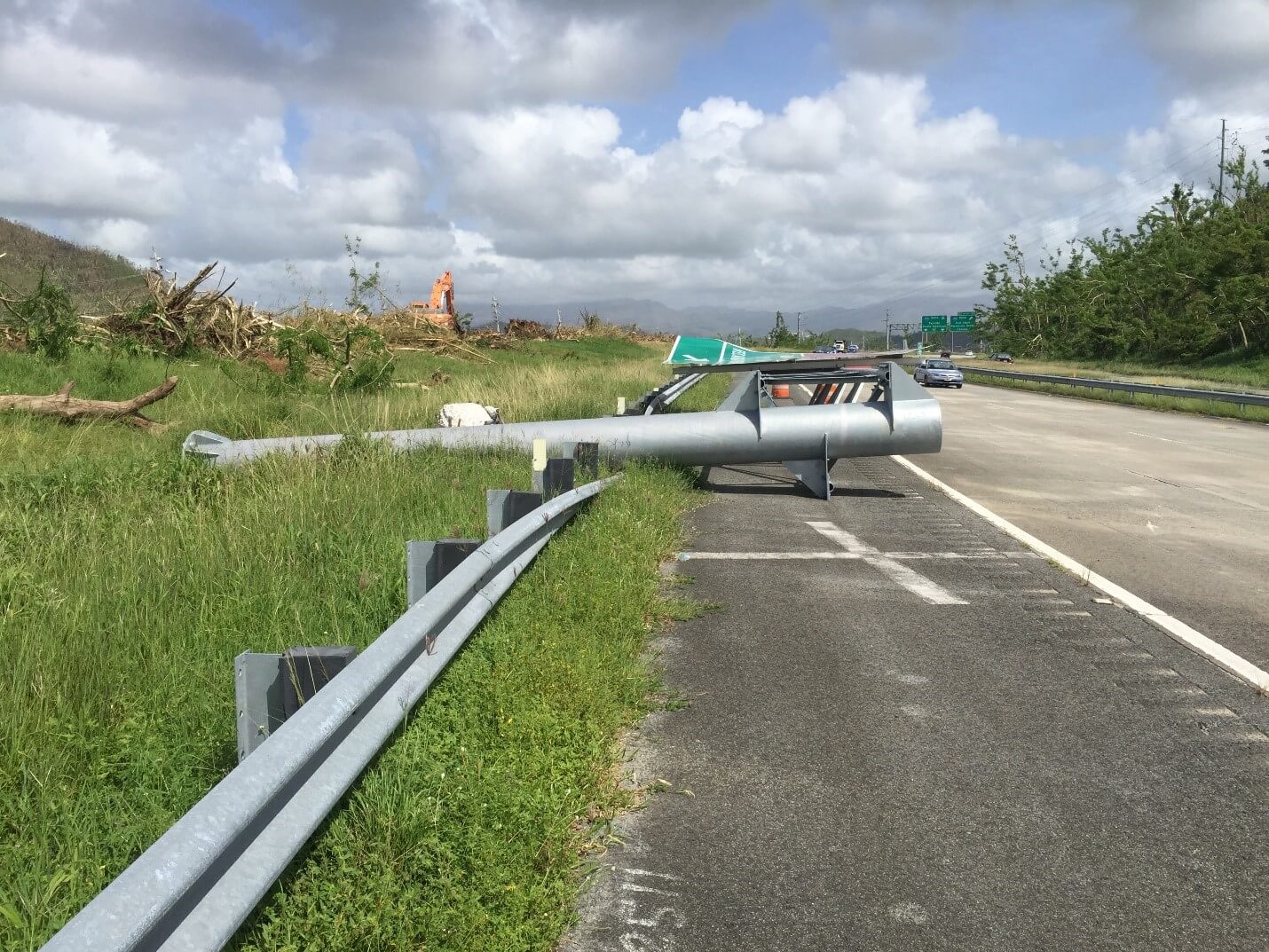 Collapsed steel truss cantilever guide sign anchored to a concrete pedestal